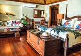 A traditional wooden room with a bed, sofa, and a wooden chest of drawers.