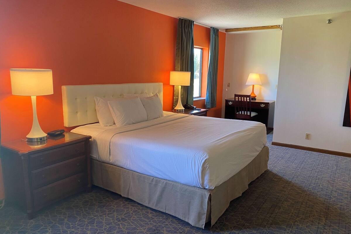 Een hotelkamer met een groot bed, twee nachtkastjes met lampen, een nachtkastje en een stoel.