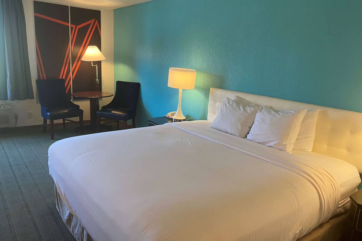 Een hotelkamer met een groot bed, twee stoelen, een tafeltje en twee lampen.