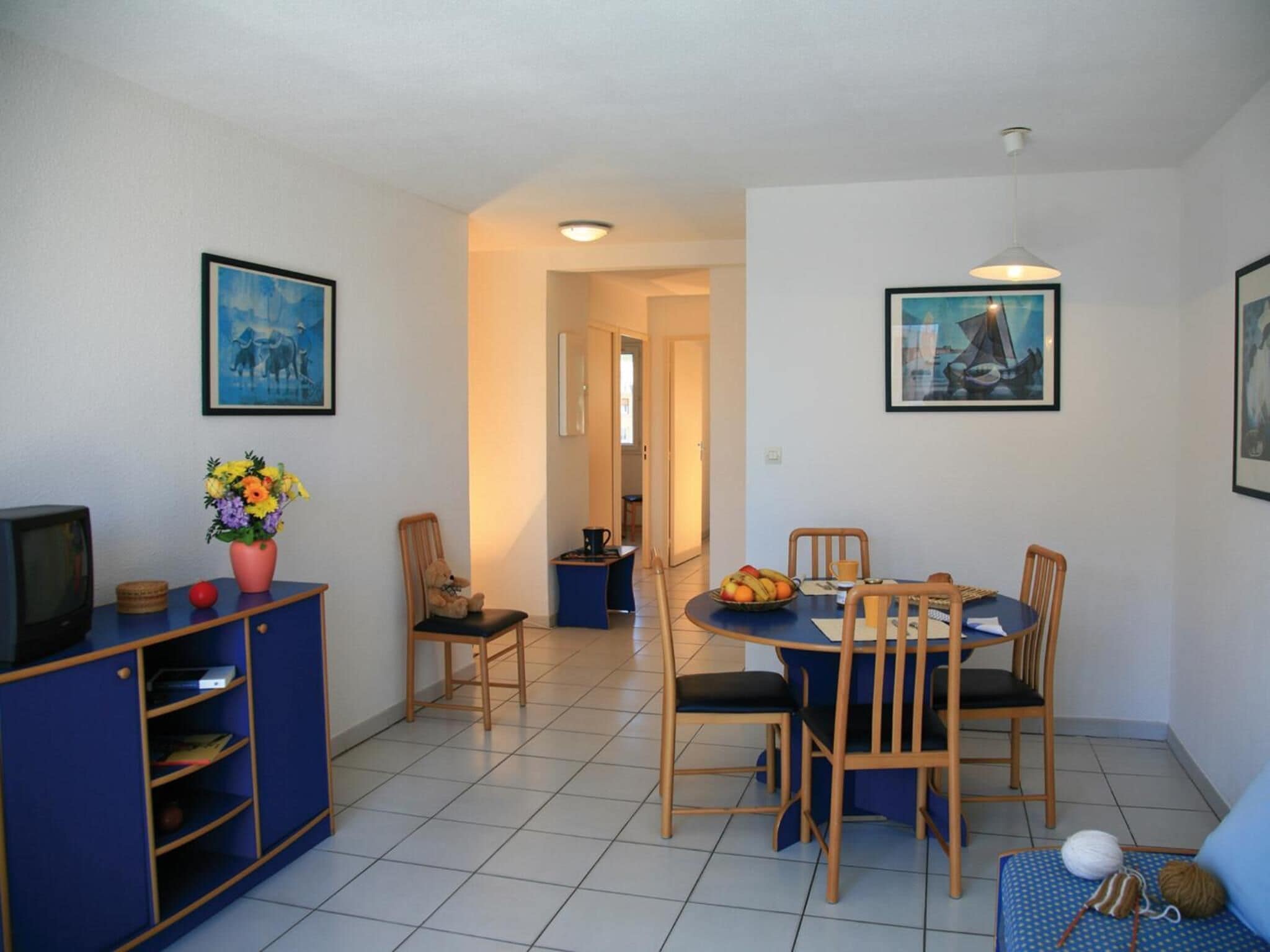 A compact living space with a dining area, a small kitchenette, and a TV.