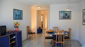 A compact living space with a dining area, a small kitchenette, and a TV.