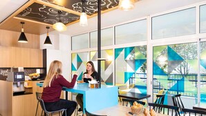 A modern café with a bar area, seating, and a view through large windows. - Aparthotel Adagio Access Paris Vanves Porte de Versailles (Vanves)
