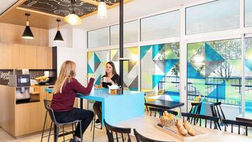 Café with a central island, coffee machine, and comfortable seating options.