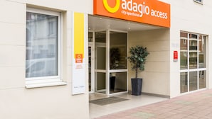The exterior of Adagio City Apartment Hotel with a large orange sign, a potted plant, and a clear entrance. - Aparthotel Adagio Access Paris Vanves Porte de Versailles (Vanves)