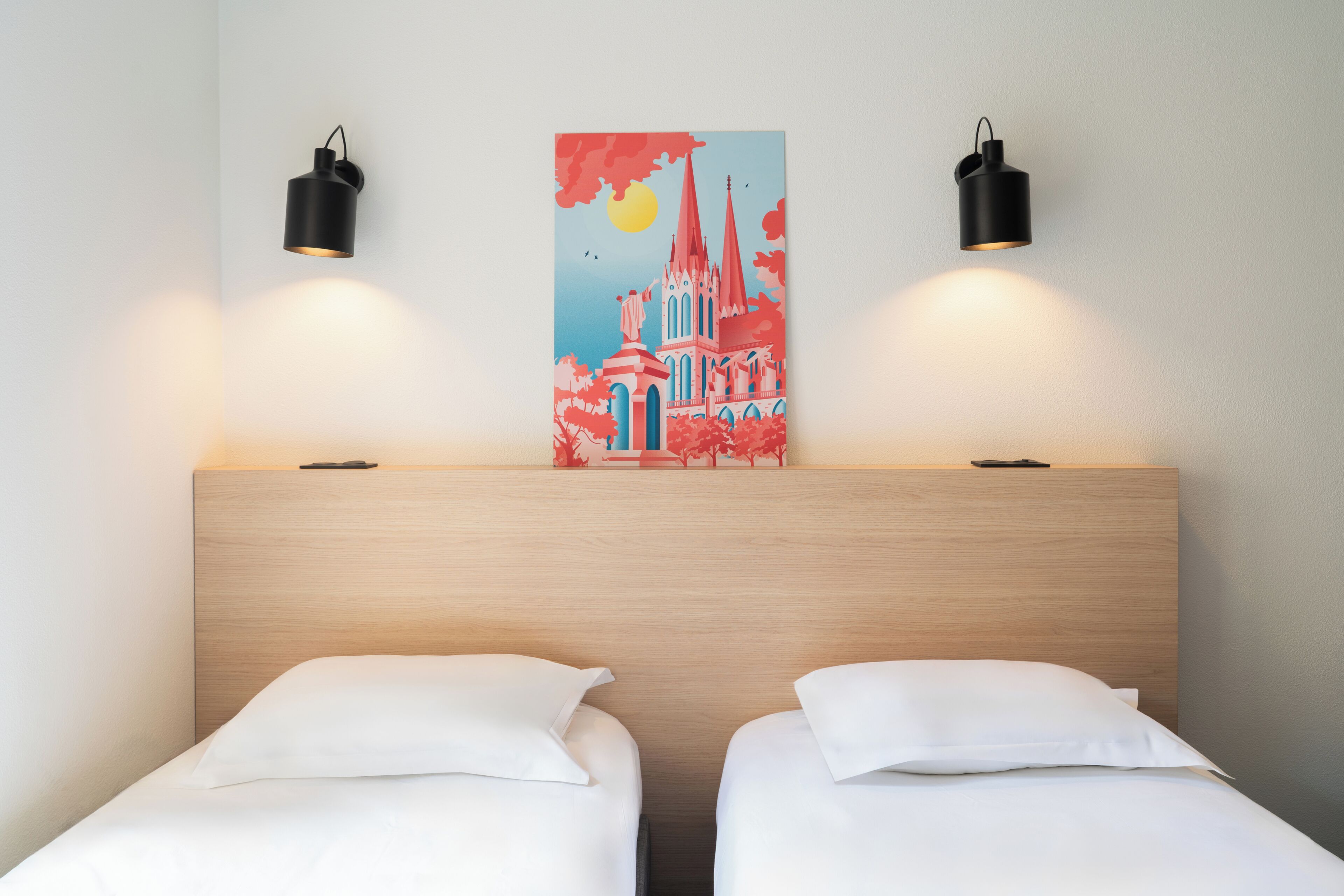 A hotel room with two beds, a wooden headboard, and a painting of a church on the wall.