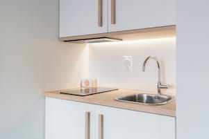 Una cocina moderna con un lavamanos de acero inoxidable, armarios de madera y una campana extractora integrada.