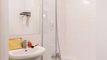 Ein Badezimmer mit Waschbecken, Spiegel, Handtuchhalter, Dusche und einer Duschkabine.