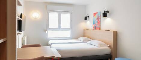 Una habitación de hotel con cama, escritorio, silla, ventilador de techo y ventana.