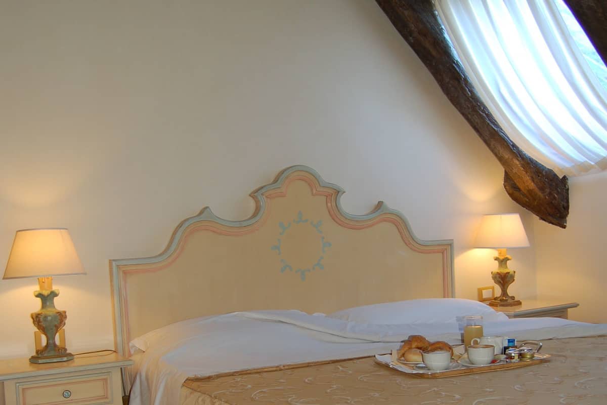 A bedroom with a large bed, two bedside tables with lamps, and a tray with breakfast items.