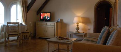 Un salon confortable avec un téléviseur, un canapé, une table et une lampe.