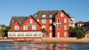 Een rood gebouw met een bord waarop 'VILLA AGUA' staat, nabij een oever.