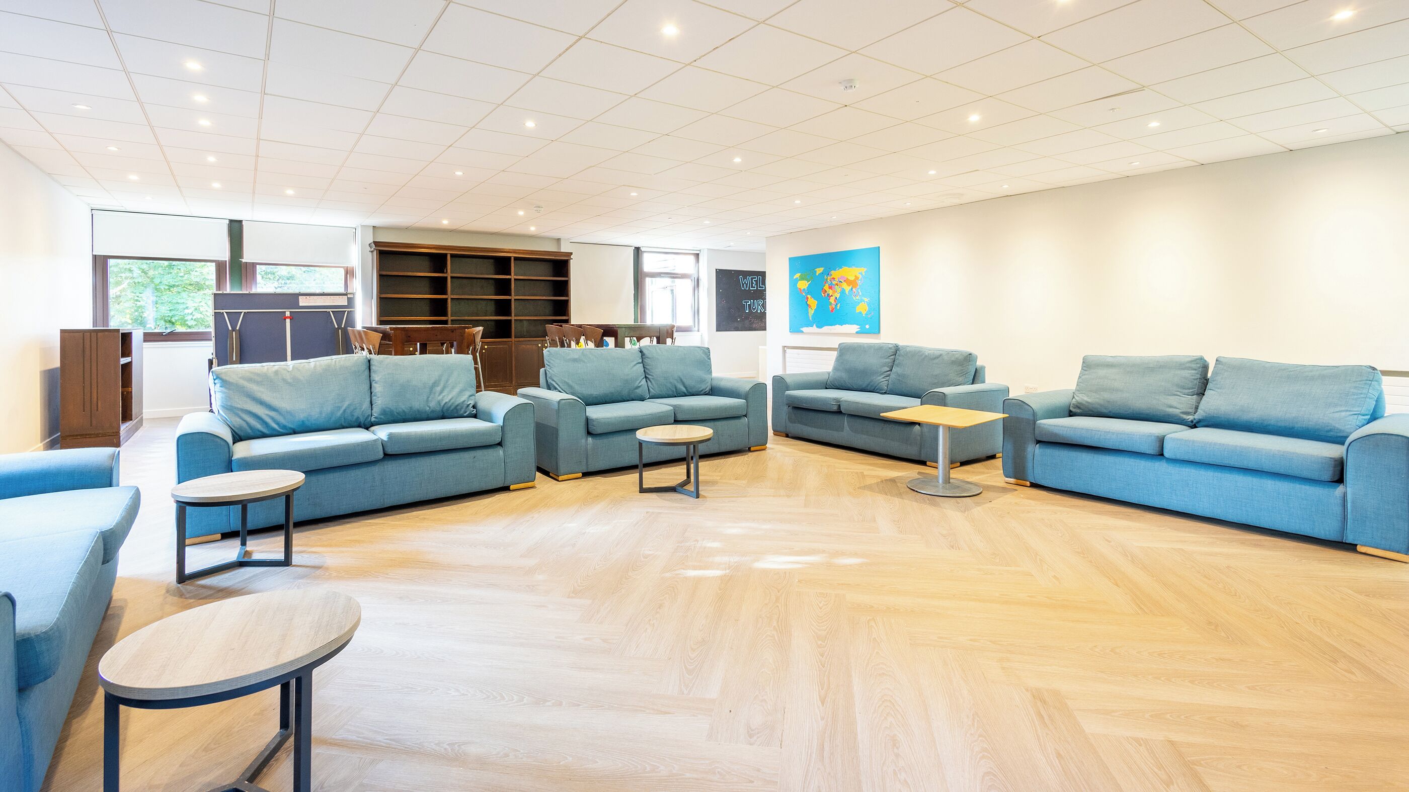 A spacious living area with multiple sofas, a wooden coffee table, and a bookshelf.