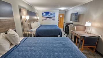 A hotel room with two beds, a desk, a chair, a TV, and a painting on the wall.