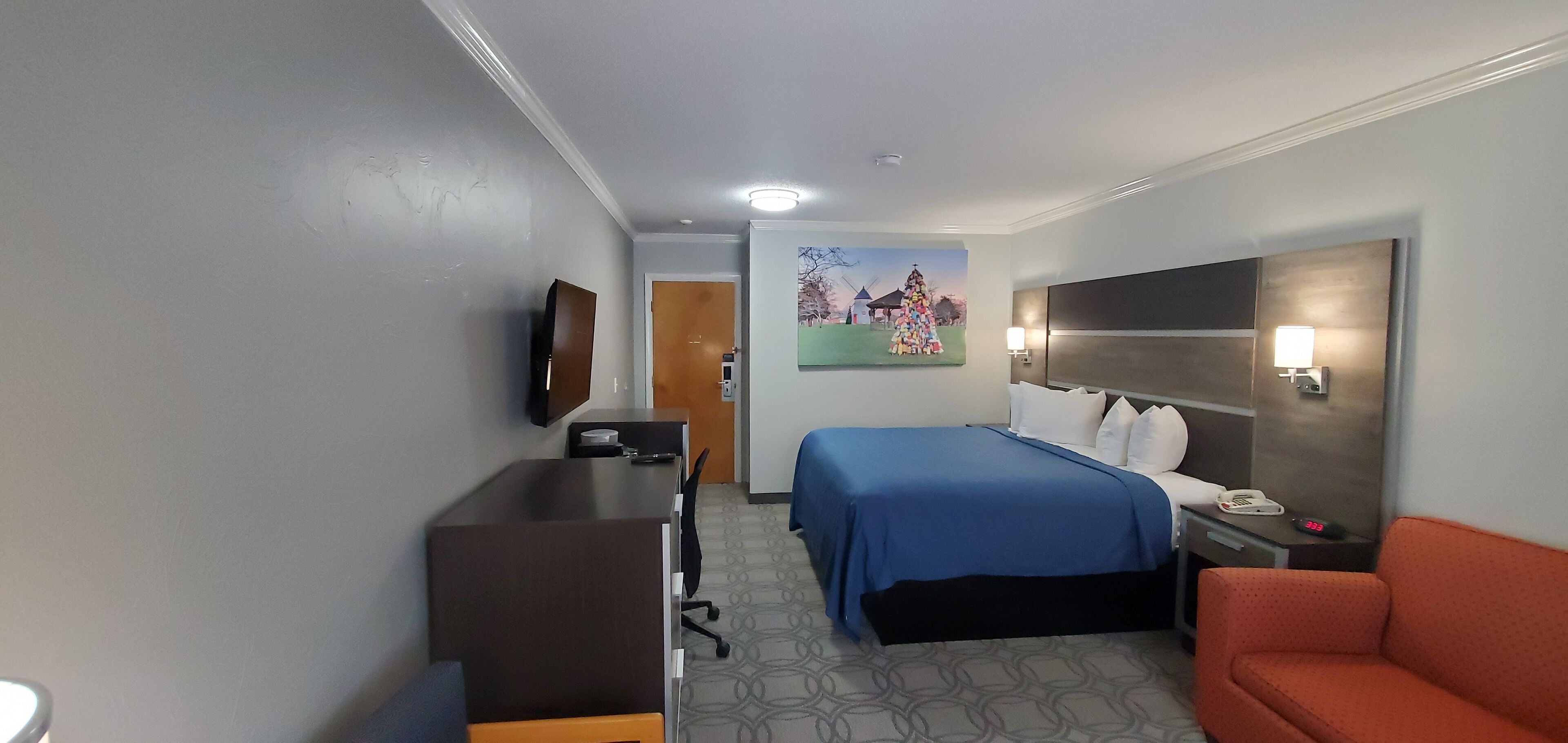 Una habitació d'hotel amb llit, escriptori, cadira i televisió penjada a la paret.