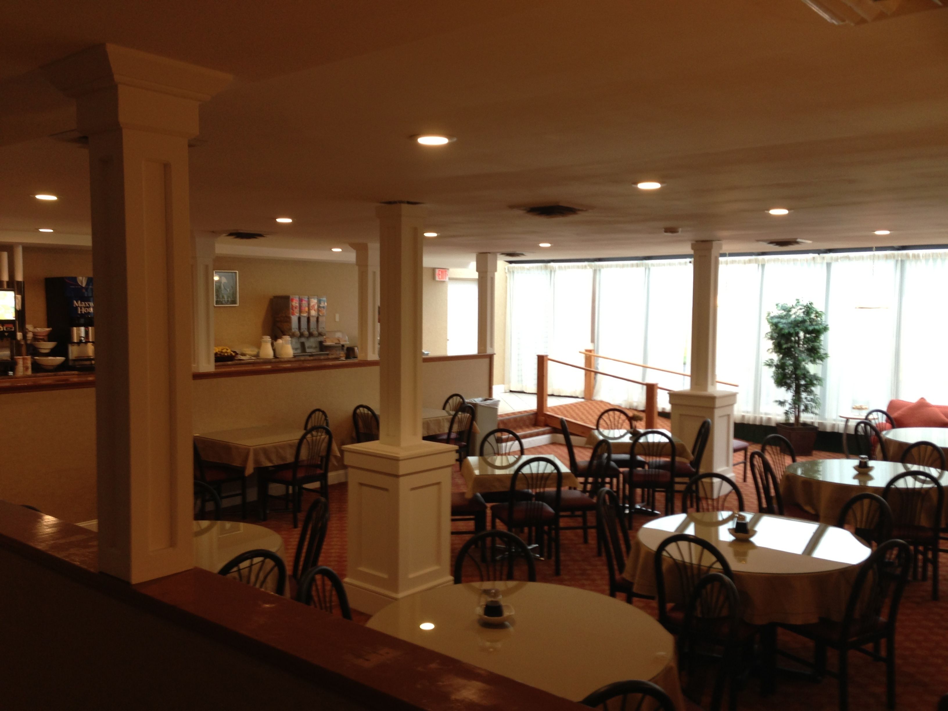 A spacious indoor dining area with multiple tables and chairs, a coffee station, and large windows providing natural light.