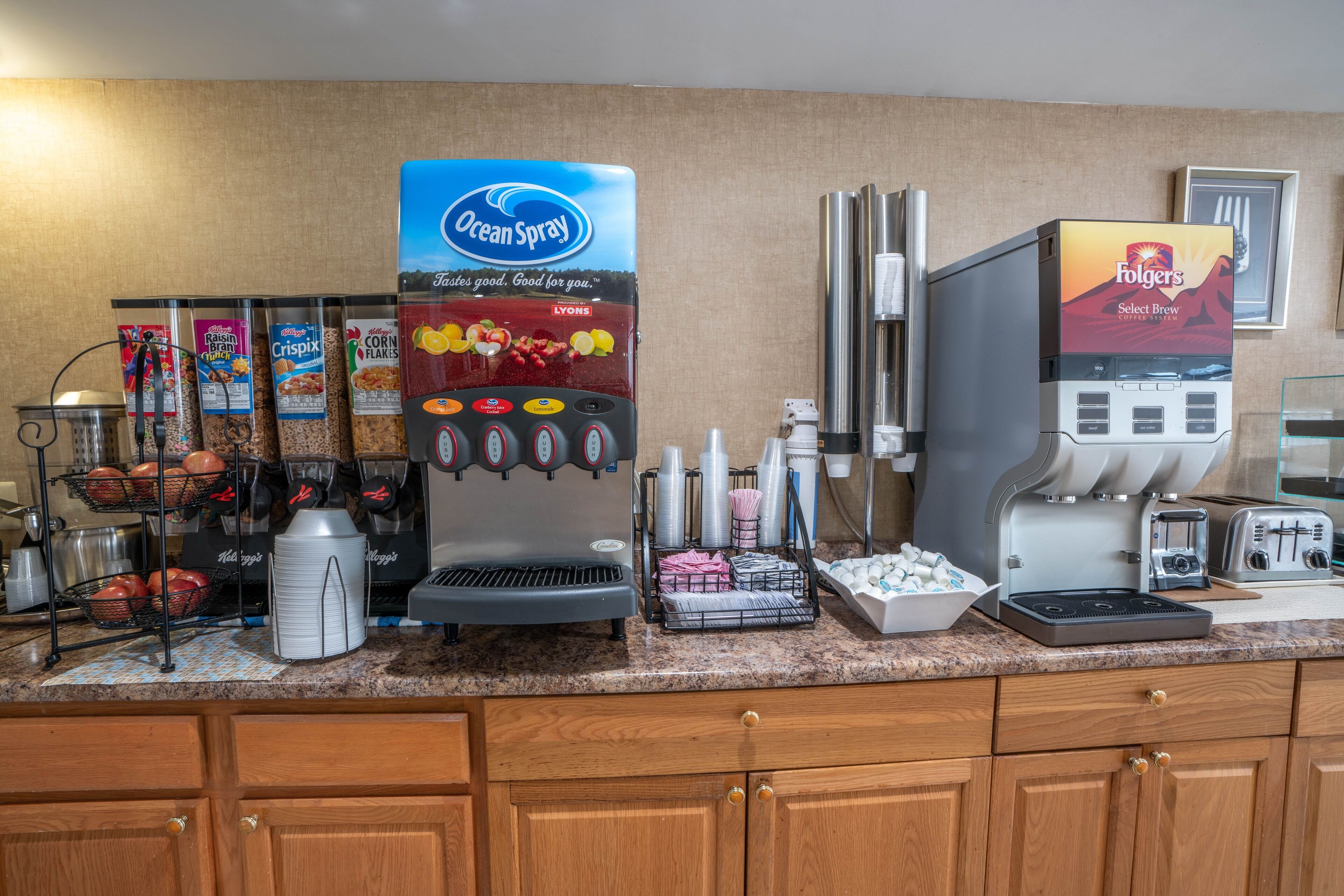 Una estación de desayuno autoservicio con diversas opciones de alimentos, como cereales y máquinas de café.