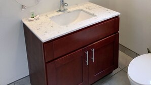 A bathroom with a white sink, a mirror, a towel rack, and a toilet.