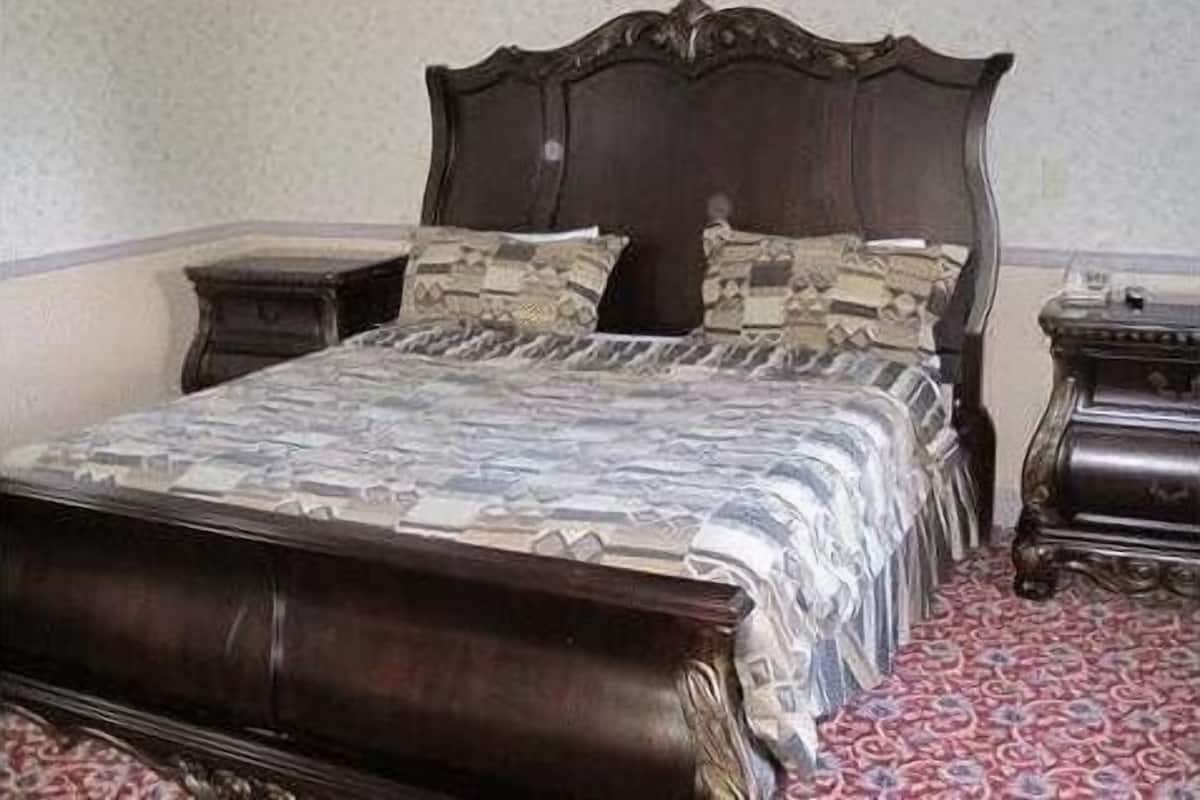 Un dormitorio con cama de madera, ropa de cama estampada y alfombra roja.