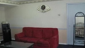 A room with a red sofa, a small table, a television, and a decorative wall piece. - Parsippany Inn and Suites Morris Plains (Morris Plains)
