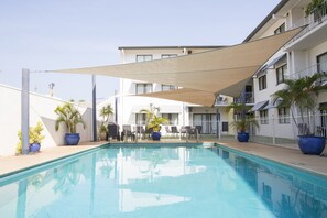 A swimming pool with lounge chairs and potted plants, surrounded by a white building with balconies. - Metro Advance Apartments & Hotel, Darwin (Darwin)