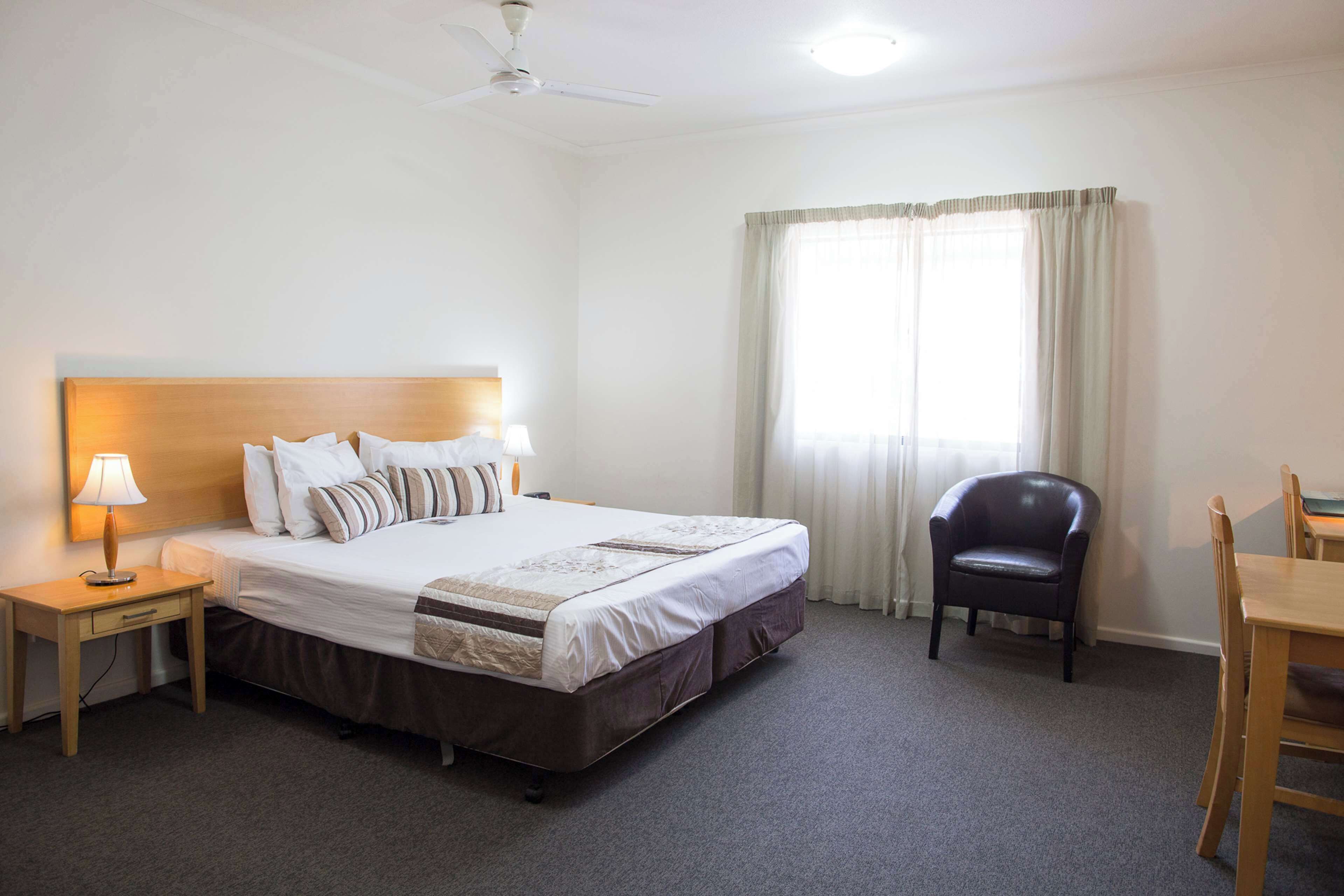 Camera d'albergo con un letto singolo, un comodino con una lampada, una sedia e un tavolo.