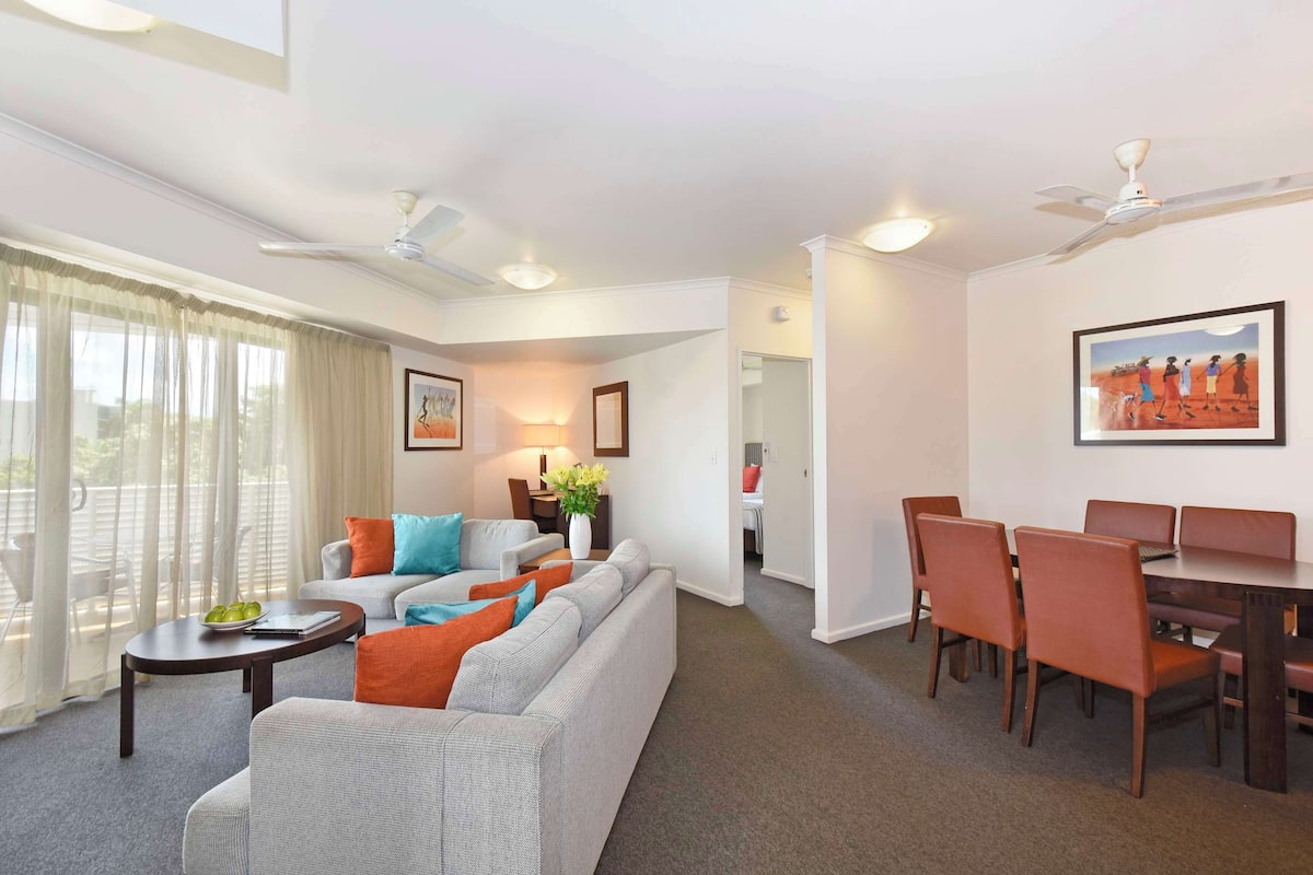 A spacious living room with a sofa, coffee table, and dining area with chairs and a table.