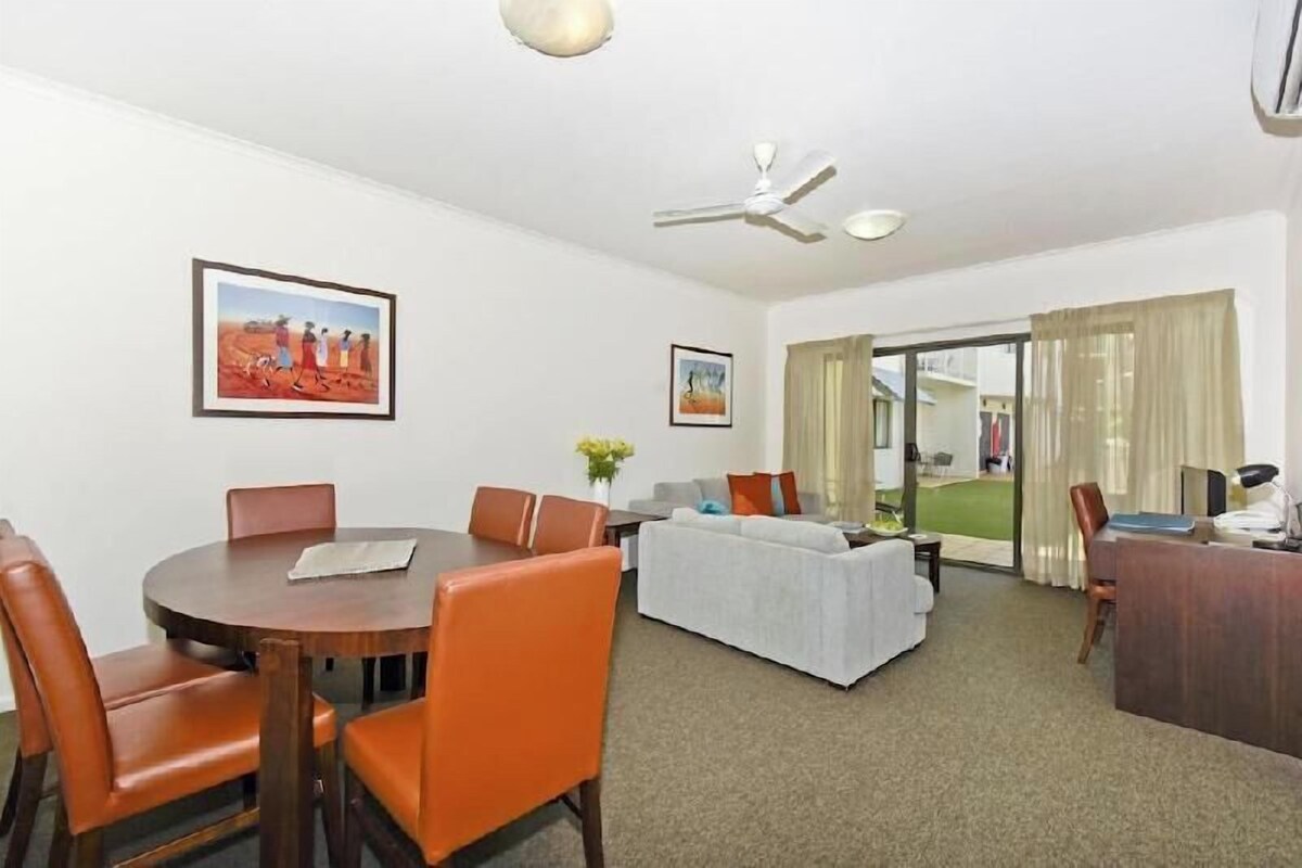 A hotel room with a dining area, a sofa, a desk, and a ceiling fan.