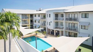 Et hotel med flere etager, en swimmingpool, altaner og udendørs siddeområder.