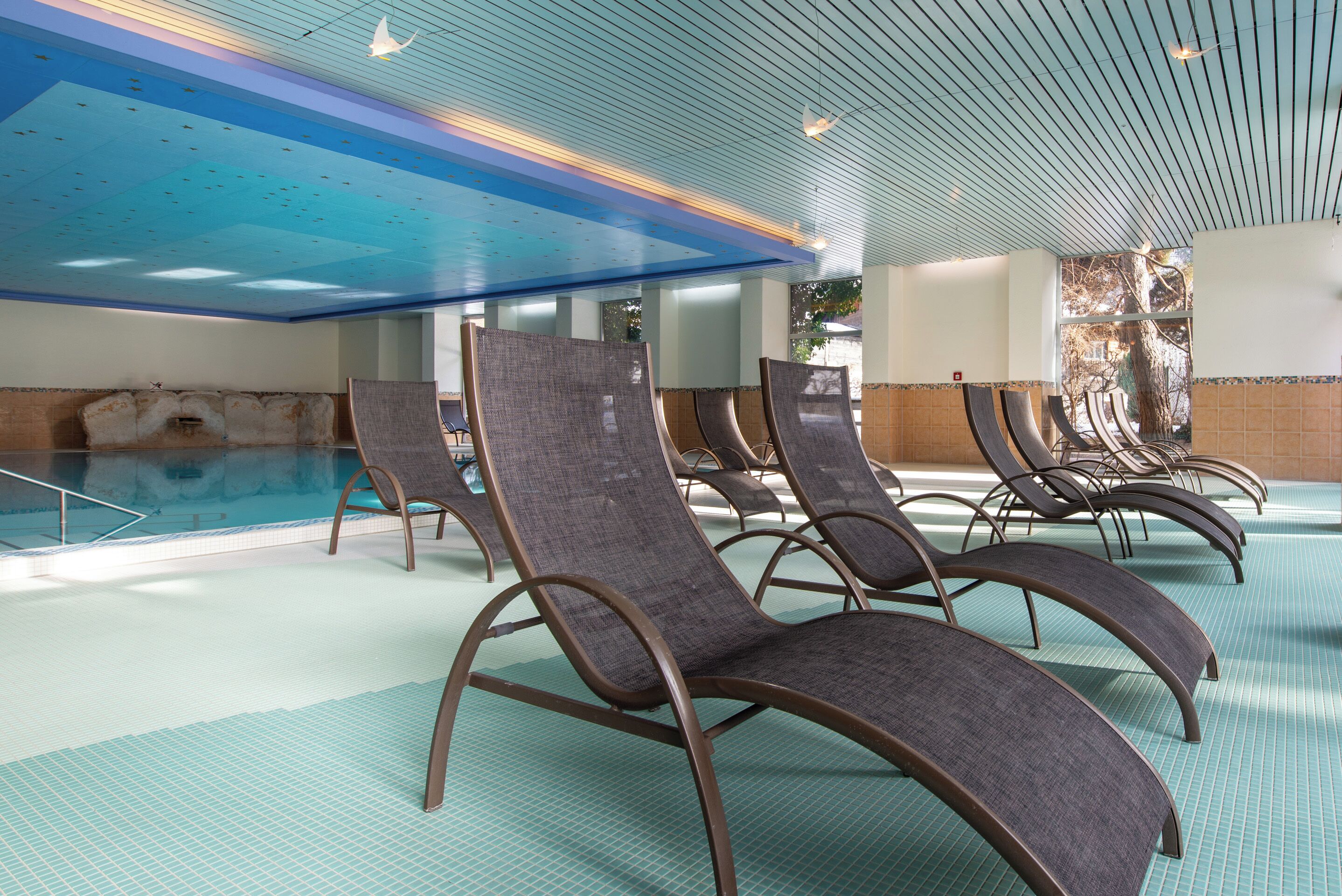 Un espace piscine avec des chaises longues et un sol carrelé.