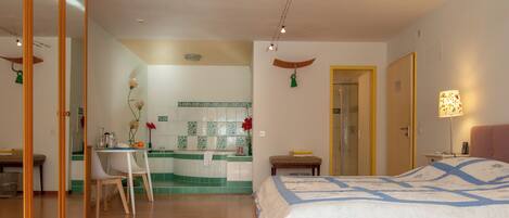 Une chambre d’hôtel avec un lit, un bureau et une salle de bain, visibles à travers une porte ouverte.