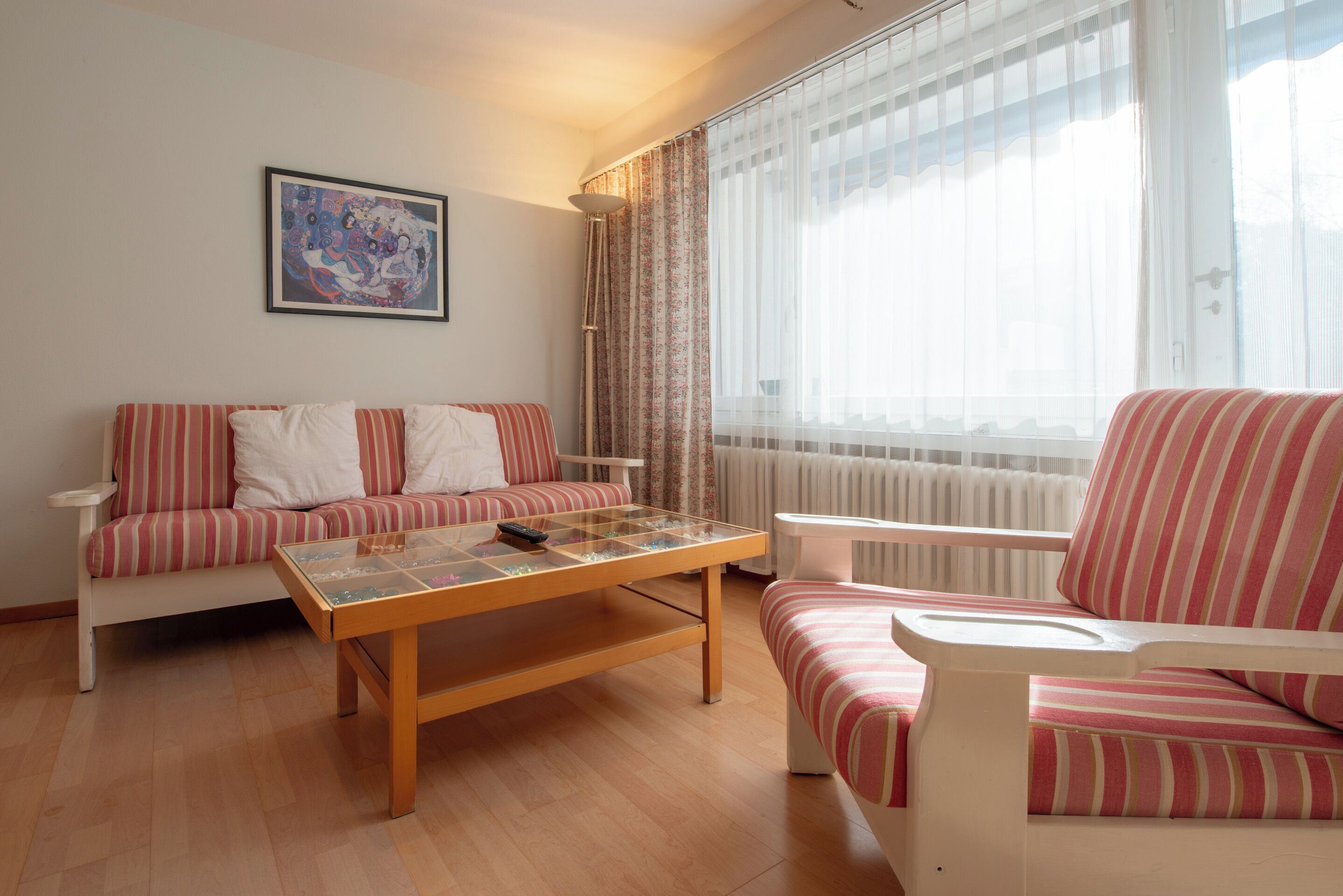 A living room with a sofa, a chair, a coffee table, and a radiator.