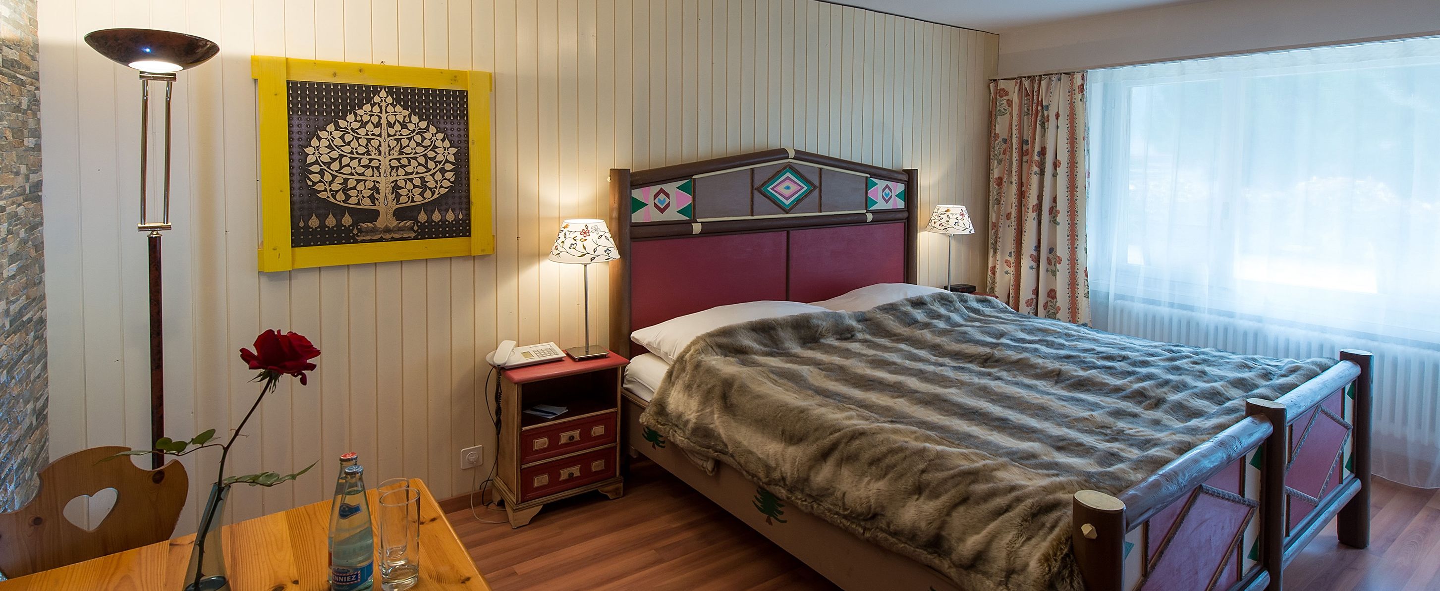 Une chambre d’hôtel comprenant un lit, une table de chevet, une lampe et une œuvre d’art accrochée au mur.