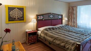 Une chambre d’hôtel comprenant un lit, une table de chevet, une lampe et une œuvre d’art accrochée au mur.