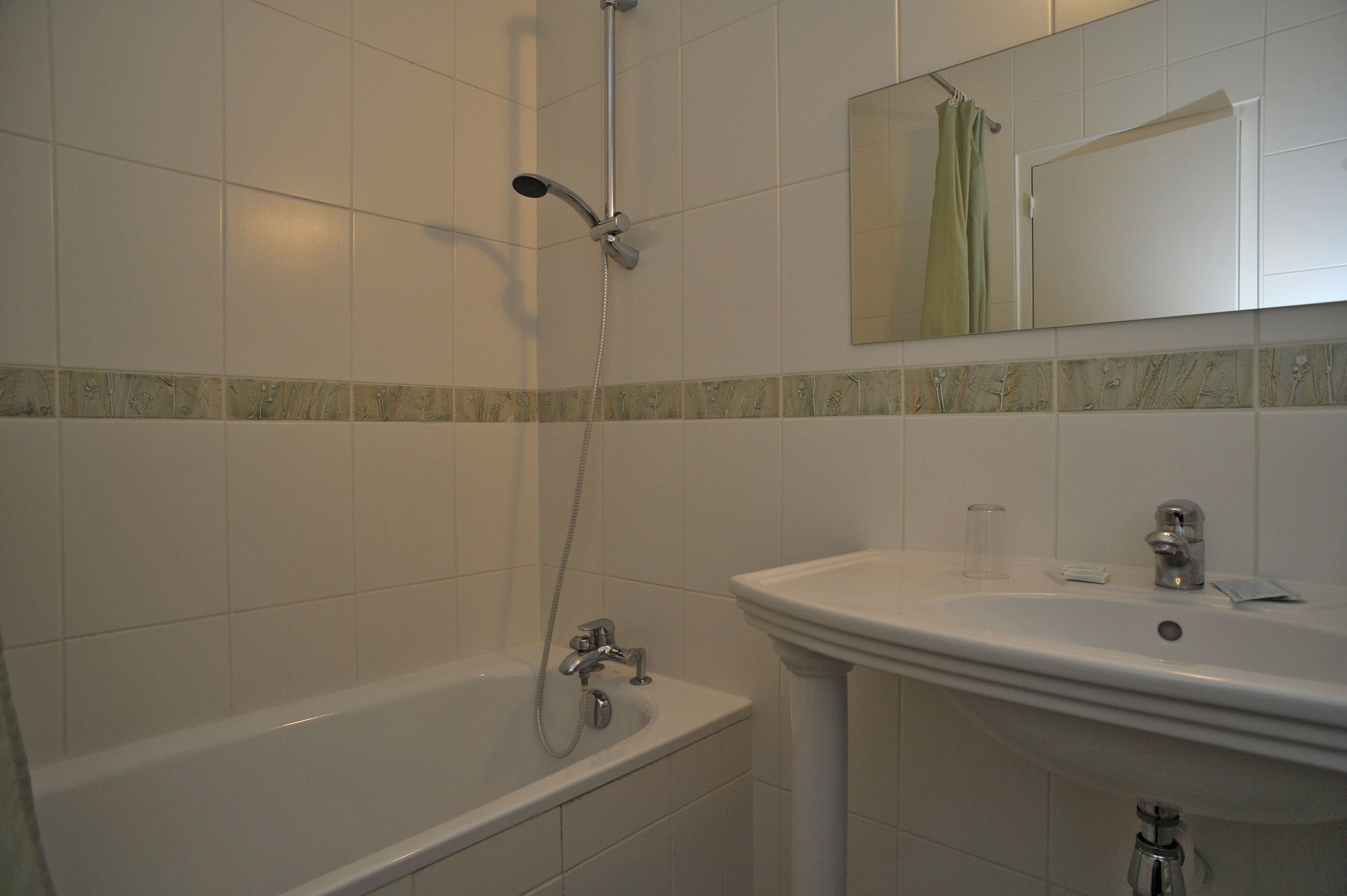 A bathroom with a bathtub, a sink, and a showerhead.