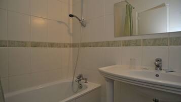 A bathroom with a bathtub, a sink, and a showerhead.
