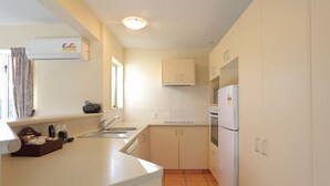 Eine kleine Küche mit weißen Schränken, einem eingebauten Backofen und einem Kühlschrank.