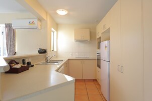 Una cocina compacta con gabinetes blancos, horno integrado y refrigerador.