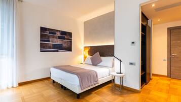 A modern hotel room with a bed, bedside table, and a wall-mounted artwork.