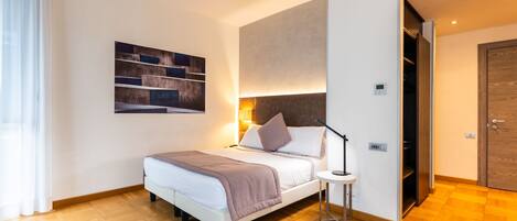 Una habitación de hotel moderna con cama, mesita de noche y una obra de arte colgada en la pared.
