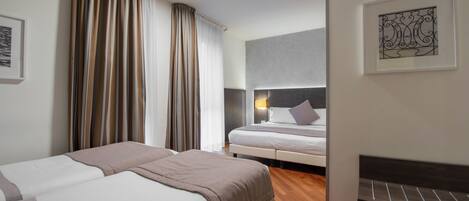 Habitación de hotel con dos camas, cabeceros, mesitas de noche, una obra de arte en la pared y una ventana con cortinas.
