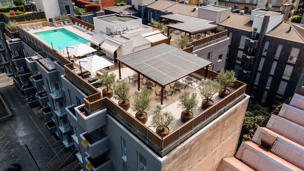 A rooftop with a swimming pool, outdoor seating, and potted plants.
