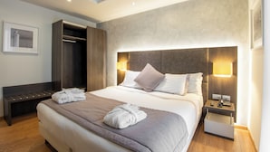 A hotel room with a large bed, bedside tables, a wardrobe, and a framed picture on the wall.