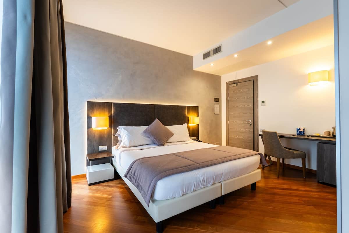 Une chambre d’hôtel moderne avec un grand lit, des tables de chevet, un bureau et une chaise.