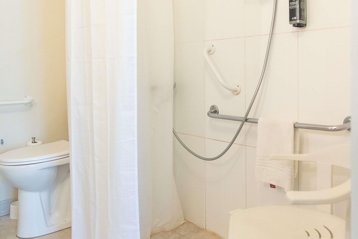A bathroom with a toilet, a shower, and a sink.