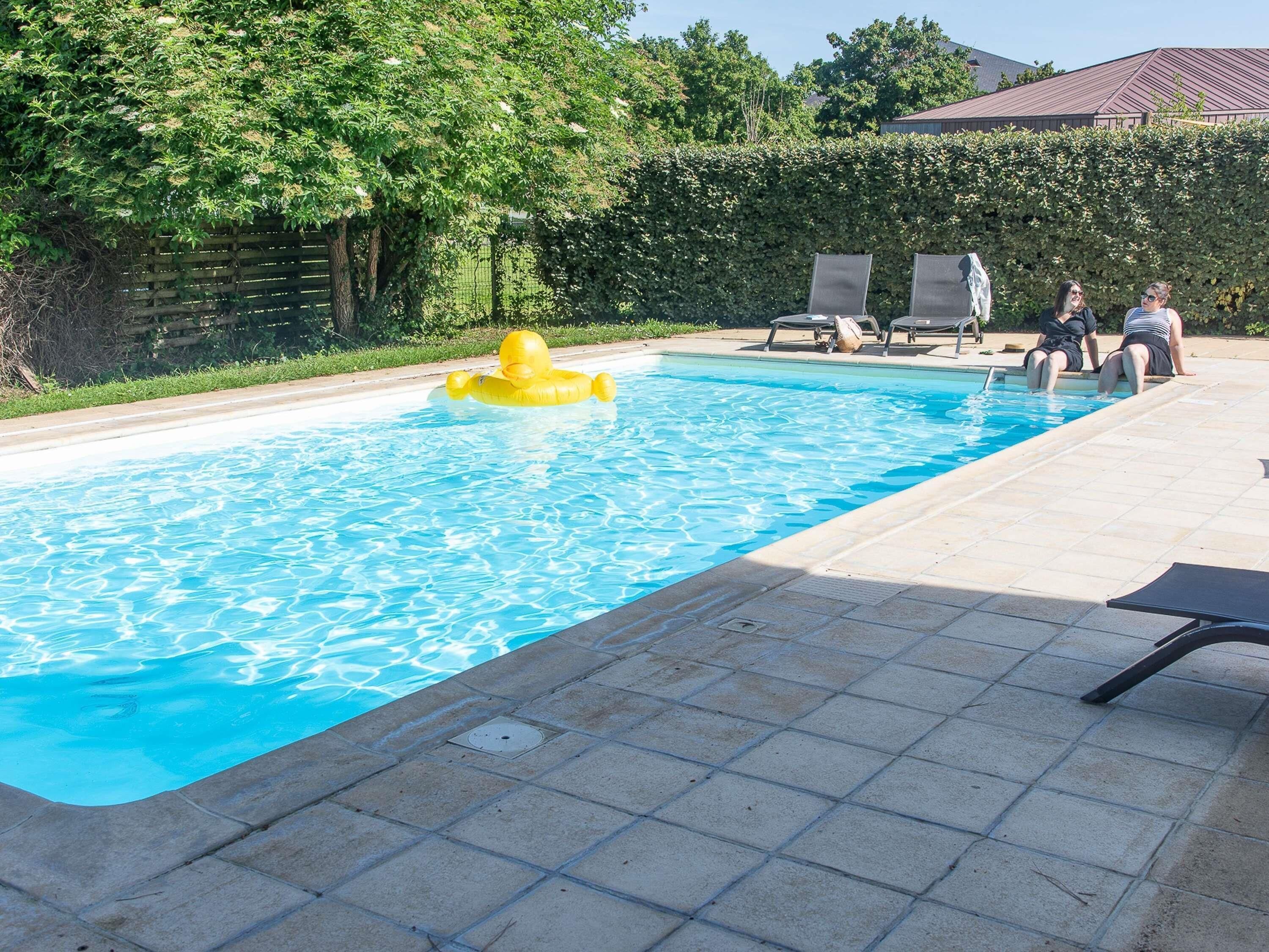 A rectangular swimming pool with clear blue water, surrounded by a tiled deck.