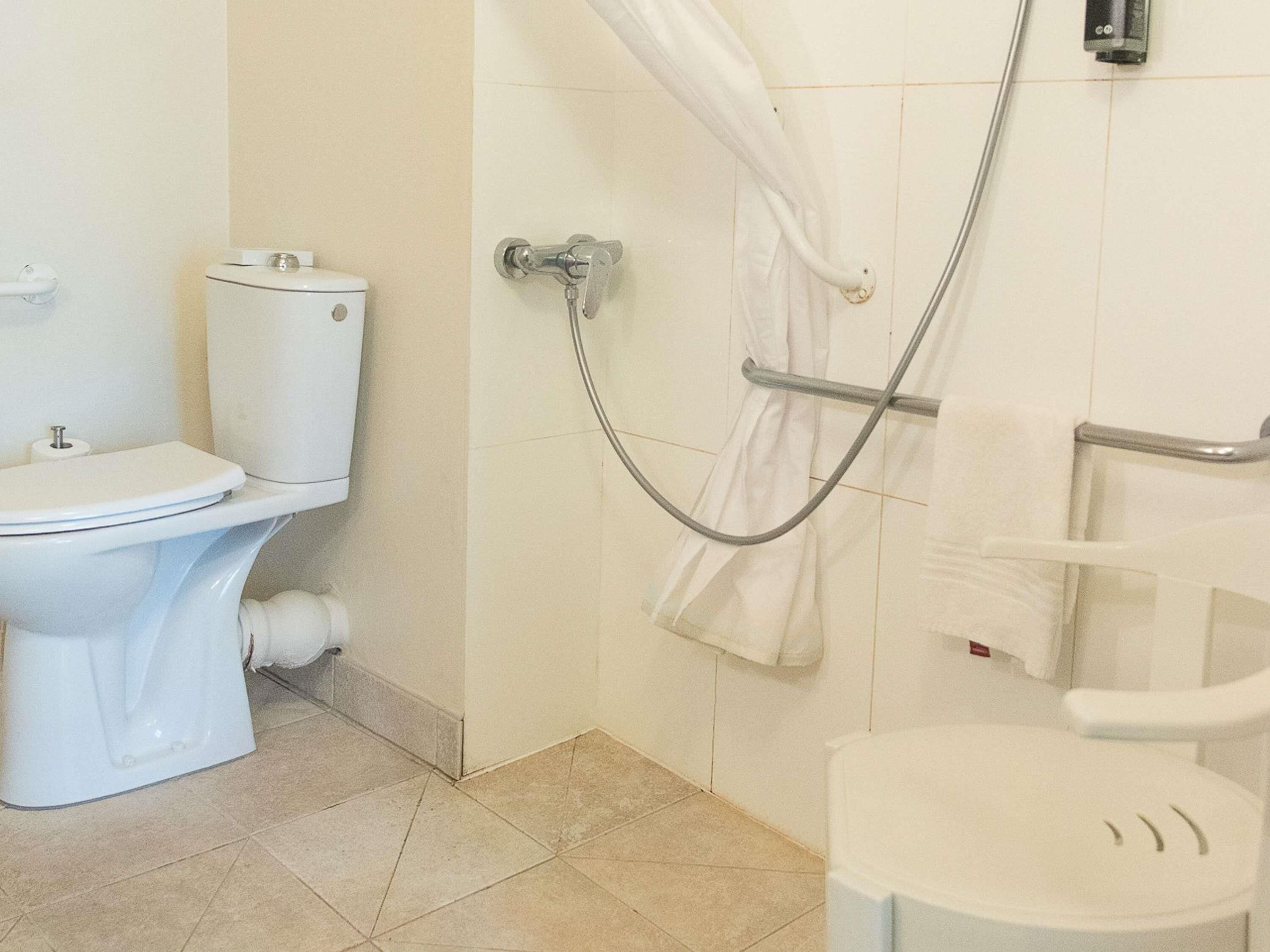 A bathroom with a toilet, a shower with a curtain, and a bidet.