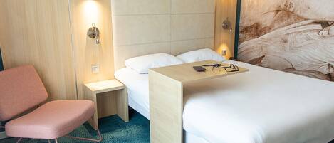 Habitación de hotel con cama, una silla, una mesita de noche y una lámpara de pared.