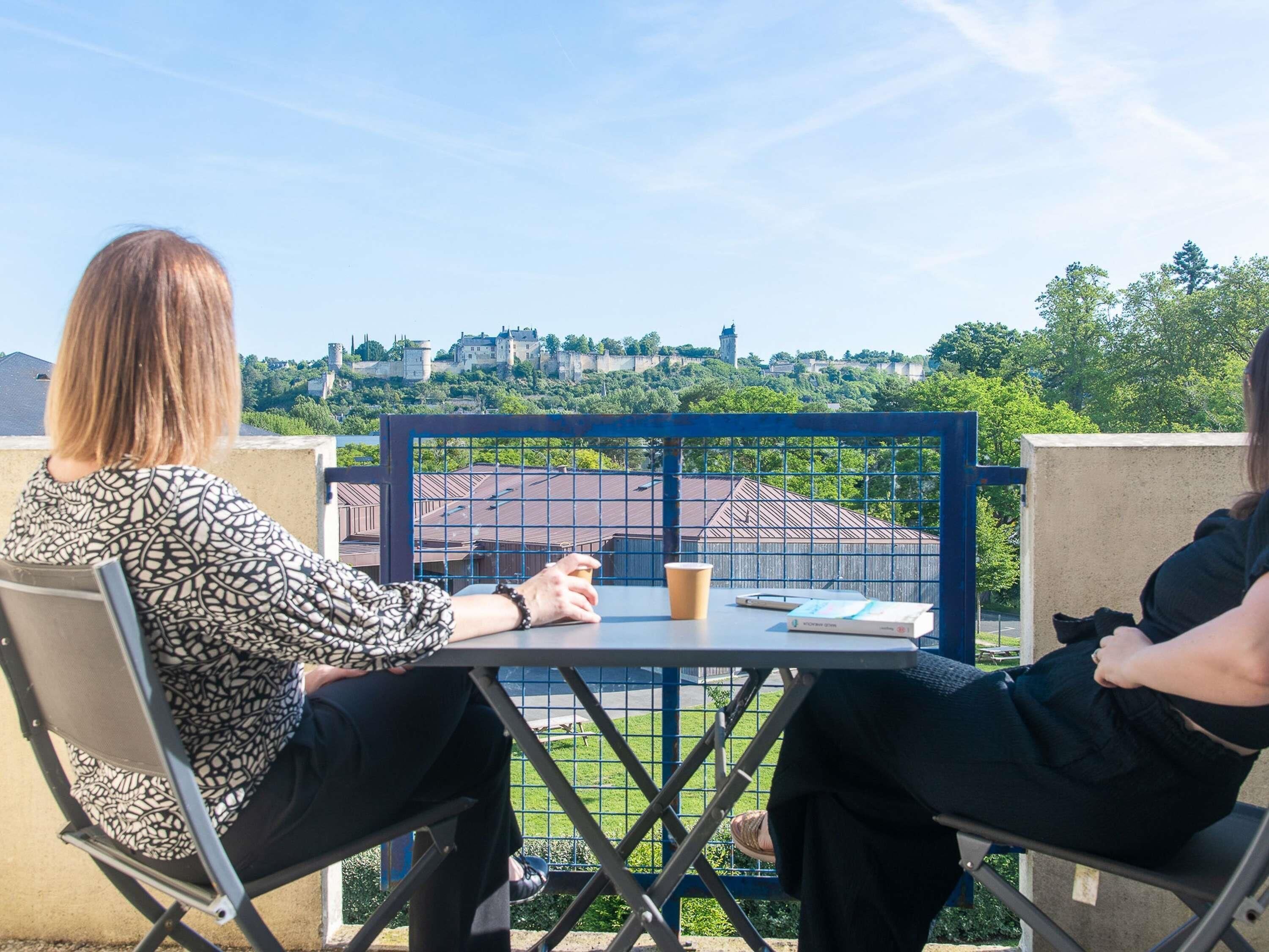 Two people seated at a table with a view of a castle and buildings in the background.