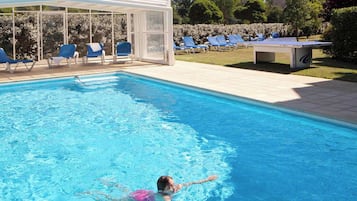 Relax by the pool surrounded by comfortable lounge chairs and a shaded seating area.