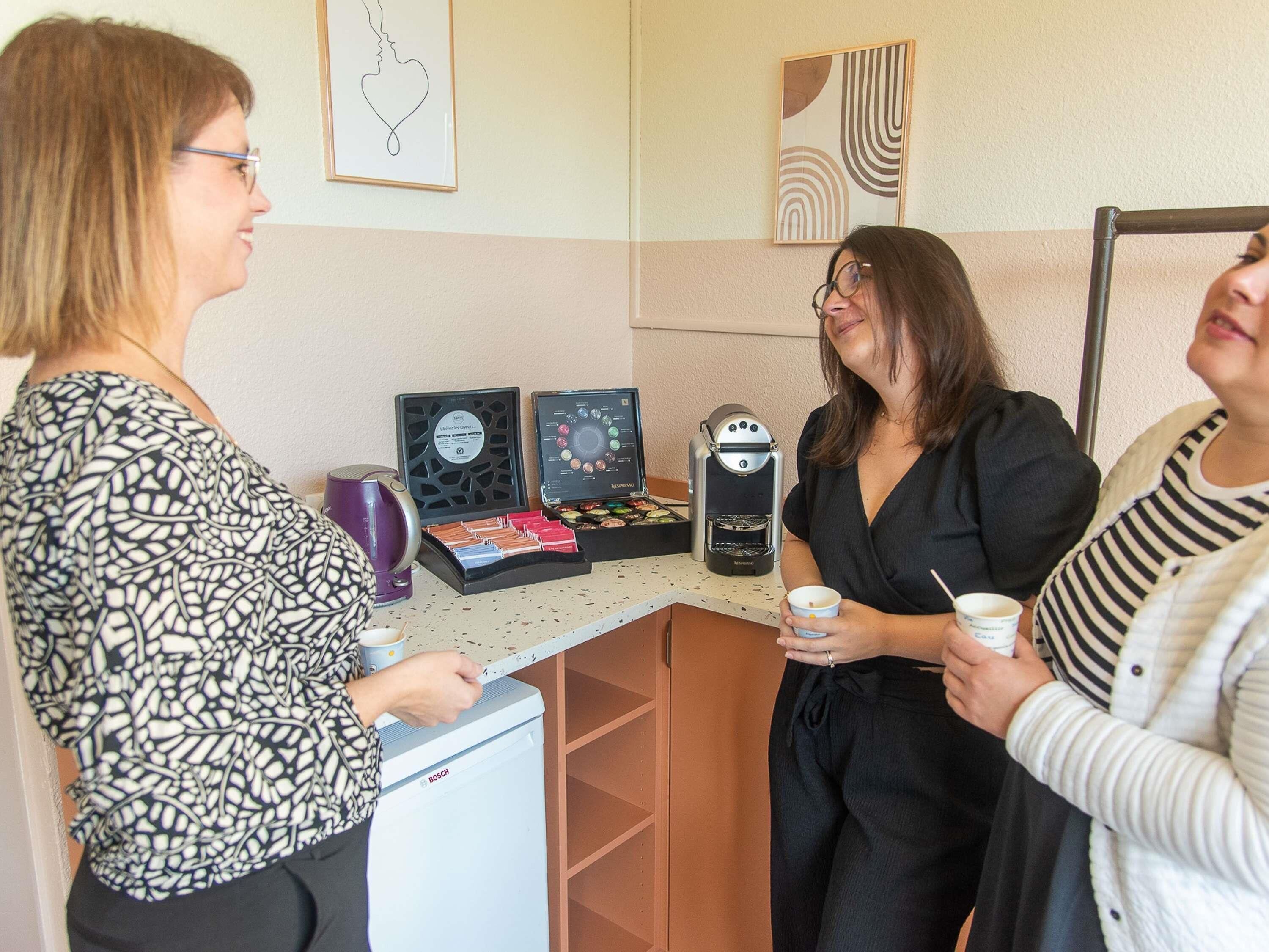 A kitchenette area with a coffee machine, a kettle, and a small refrigerator.
